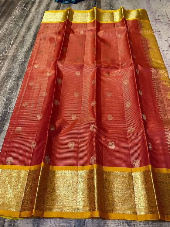 Brick red silk saree with gold buttis and a broad mustard zari border